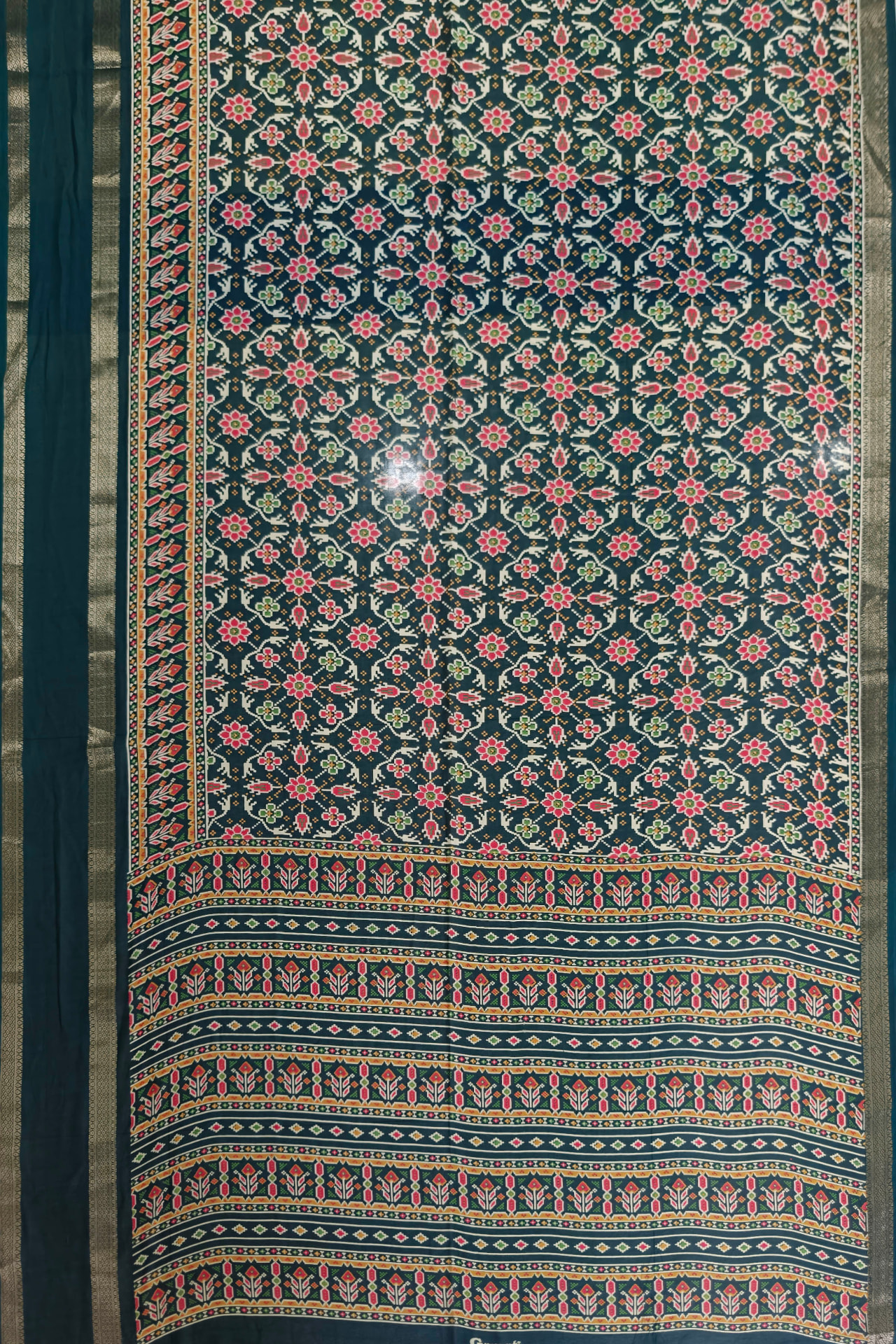 Flat-lay photograph of a saree fabric filling the frame with visible borders